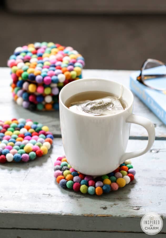 multicolored felt ball coasters with a cup of tea.