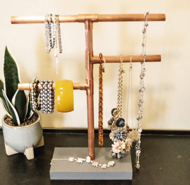 Copper pipe jewelry stand with jewelry.