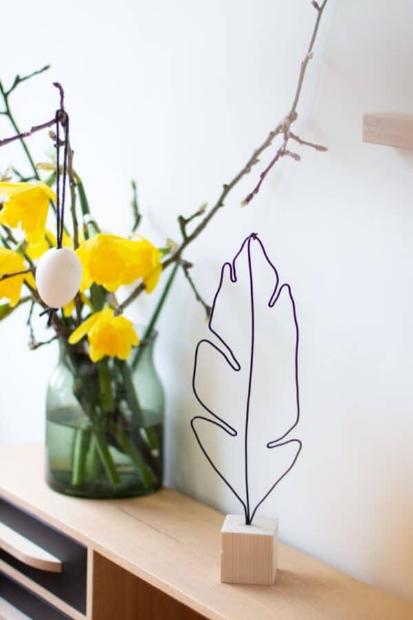 Wire feather ornament in wooden block.