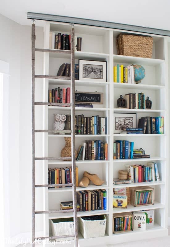 Tall white fitted bookshelves with moving library ladder.