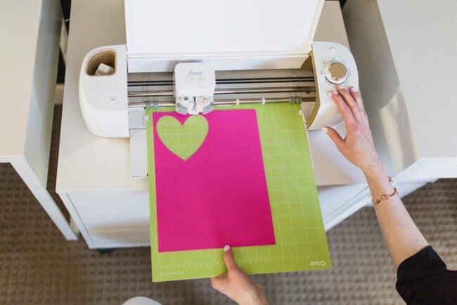 Cricut machine cutting out a pink felt heart.