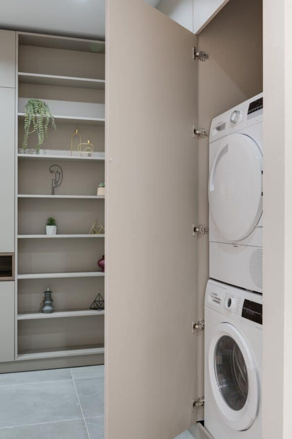 Washing machine and dryer stacked on top of one another in laundry room.