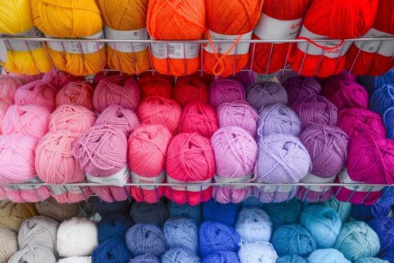 Shelf of different colored knitting yarns.